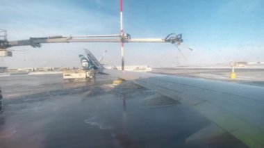 LOS ANGELES, CALIFORNIA, ABD-30 EKİM 2023: Makine havaalanındaki uçak kanadına krema önleyici sıvı püskürtüyor. Kalkıştan önce yolcu uçağını buzdan arındırıyorum. Westjet uçağı kalkışa hazırlanıyor.