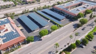 Calabasas 101 karayolu boyunca bulunan küçük güneş enerjisi santralinin insansız hava aracı çekimi, Los Angeles, Kaliforniya, ABD. Yolda giden arabaların hava manzarası. İstasyondan güneş panelleriyle yüklenen elektrikli otomobiller