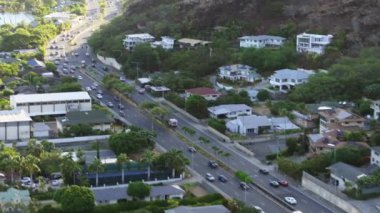 Sirenli acil servis arabası hızla hastaneye gidiyor. Hawaii 'deki küçük bir kasabada acil durum. Altın günbatımı ışığı 4K insansız hava aracı atışı, ABD. Yeşil Oahu adası Hawaii 'de hızla giden ambulans aracı.