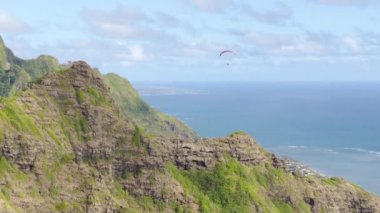Kualoa Çiftliği 'nin çekim yeri, bakış açısı. Oahu Adası, Hawaii USA ekstrem sporu. Pilot gökyüzünde maceraperest ekstrem sporlar yapıyor. Pasifik Okyanusu kıyısındaki Hawaii yabanı üzerindeki havadan kıyı manzarası
