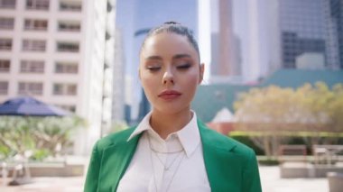 İdari lider portresi, iş merkezinin önünde duran girişimci 4K. Kendine güvenen genç iş kadını açık havada vesikalık portre için poz veriyor. Profesyonel pazarlama müdürü yüzü