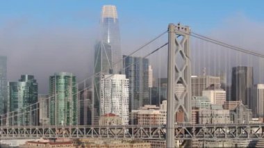 Sinema İHA 'sı, asma Bay Köprüsü' ne paralel hareket halindeki San Francisco şehir merkezli. Finans bölgesinde sabah sisi ile kaplanmış iş ofisleri 4K USA