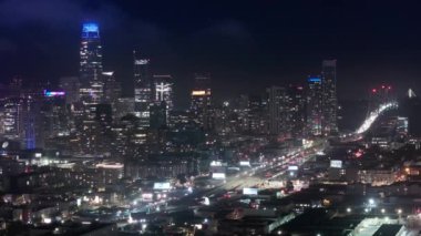 San Francisco şehir merkezindeki hava uçuşu gece aydınlandı. Gece trafiği panorama 4K insansız hava aracı atışı. San Francisco gece binaları şehir merkezi silueti. Gökdelenler finans bölgesi