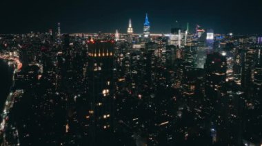 Aydınlanmış Manhattan USA. New York şehrinin arka planı. Hava Saati Meydanı şehir merkezi panoraması. Karanlık çöktükten sonra gökdelenler üzerinde İHA uçuşu.