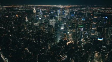 Hava Saati Meydanı şehir merkezi panoraması. Karanlık çöktükten sonra gökdelenlerin üzerinde İHA uçuşu. Gece vakti modern gece şehrinin üzerinde. Aydınlanmış Manhattan USA. New York Şehri arka plan görüntüsü