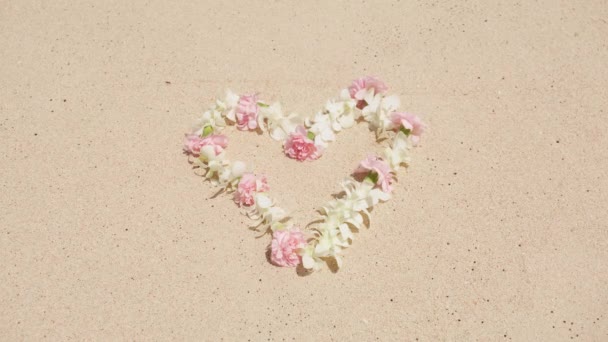 爱情的象征是花的心形躺在白沙滩上 传统夏威夷鲤鱼项链上的白色和淡红色热带花 爱情概念 情人节 婚庆背景 — 图库视频影像