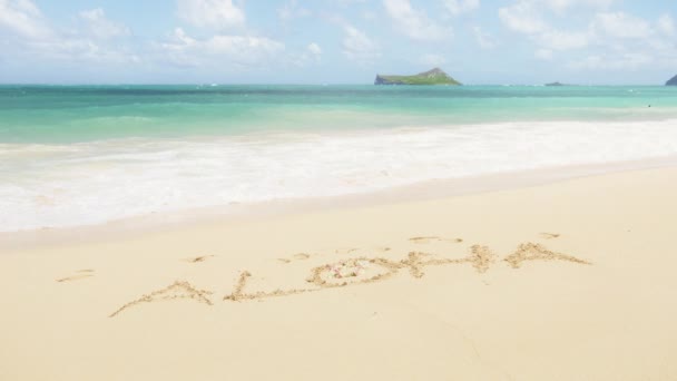 在瓦胡岛热带夏威夷海滩的沙子上写下的阿罗哈字 在夏威夷异国情调的岛上 爱荷华州欢迎被海洋泡沫波冲走的信息 天堂岛暑假旅行背景 — 图库视频影像
