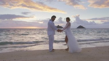 Beyaz boho tarzı gelinlik giyen romantik aşıklar egzotik adada kaçma törenine hazırlanıyorlar. Gelin ve damat kumsalda tropik günbatımının keyfini çıkarıyorlar. Balayı tatili 4K