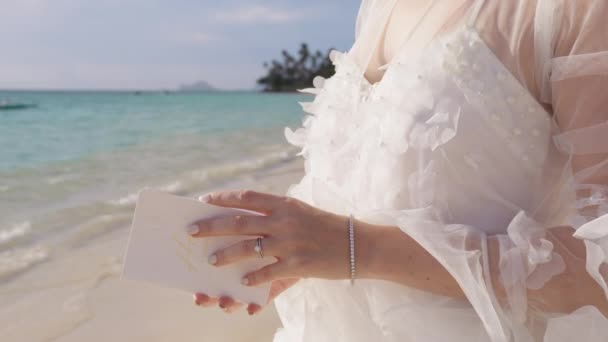 エループの背景 美しい白い花のブーフのウェディングドレスで認識できない花嫁は ビーチの結婚式で成長することを誓います 花びらを抱いた女性の手のクローズアップショット — ストック動画