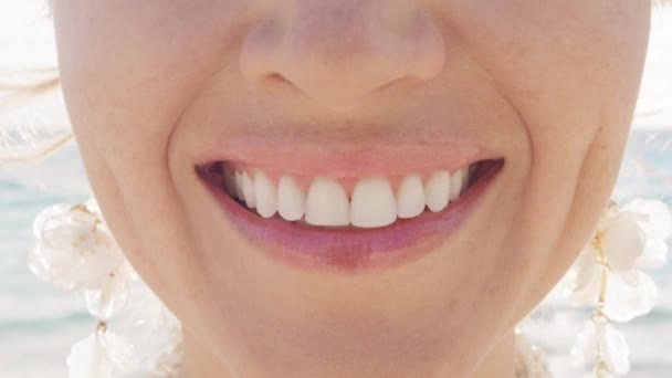 スローモーションでカメラに微笑んでいる幸せな白人女性のクローズアップ 見えない歯の後白い笑顔を示す女性は 屋外の晴れた背景で手順を整列します ストマトロジーと歯科医療のコンセプト — ストック動画