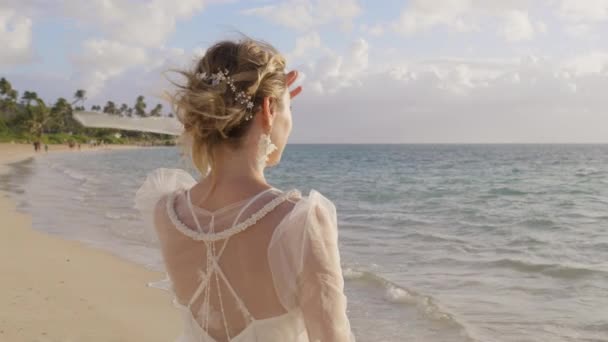 年轻女子穿着时髦时髦的波荷风格的白色纯花婚纱 望着大海 浪漫的新娘站在热带海滩上的倒影 海滩婚礼 美好未来 蜜月假期 — 图库视频影像