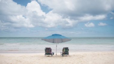 Güzel Waimanalo plajı, Oahu Adası, Hawaii ABD. Renkli plaj sandalyeleri ve mavi okyanusun yanında güneş şemsiyesi. Yaz tatili ve turizm için tatil konsepti. İlham verici tropikal manzara 4K