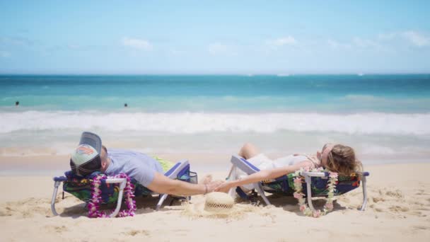 安详快乐的年轻人牵着女人的手躺在舒适的海滩椅子上 安详祥和的男人和女人在椅子上呼吸新鲜的海洋空气 享受无忧无虑的暑假 — 图库视频影像