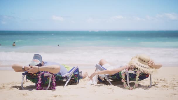 家族カップルは 素晴らしいライトブルーの海で白い砂浜のビーチチェアでリクライニングされたビーチで日光浴 ハワイ米国4Kの夏休みにトロピカルパラダイス島でストロー帽子の男女 — ストック動画