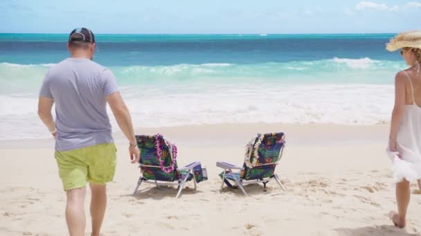 ビーチチェアに裸足を歩く美しい振りドレスの若い女性 素晴らしい青い海で手を握る愛のゆっくりとした動きの男と女性 ハワイ州オアフ島の夏休みの旅行者カップル — ストック動画