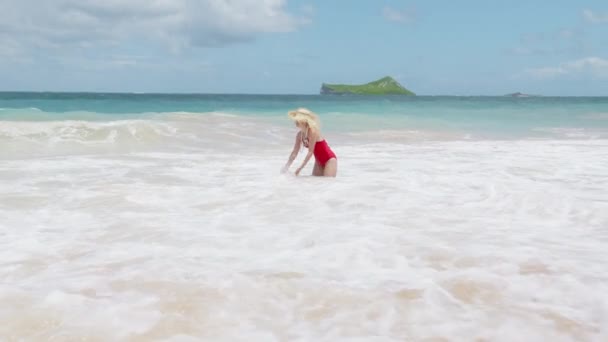 赤い水着の美しい女性は 嵐の海の波で泳いでいます 泡立ったターコイズの海のわら帽子の若いセクシーな女の子 パラダイスオアフ島での休暇 オーシャンリラックス ハッピーライフスタイル ハワイ島への旅行 — ストック動画