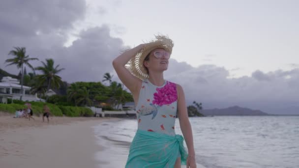黄昏时分 穿着蓝色泳衣在瓦胡岛海滩散步的美丽的女游客 暑假快乐的女性游客享受着热带电影般的自然生活 微笑的女人踏上夏威夷异国情调的旅程 — 图库视频影像