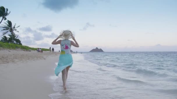身穿蓝色沙滩的女性 戴着草帽 享受着电影般的自然生活 前往热带天堂夏威夷岛复制空间背景 日落4K后在异国情调的海滩上散步的年轻女子的相机 — 图库视频影像