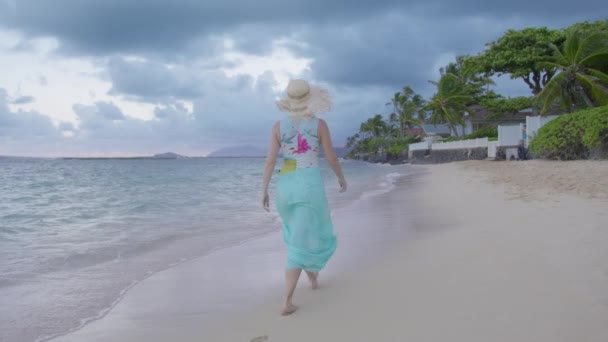 日落后在异国情调的海滩上散步的年轻女子的相机 穿着蓝色海滩的游客 戴着草帽 享受电影般的自然生活 前往热带天堂夏威夷岛复制空间背景 — 图库视频影像