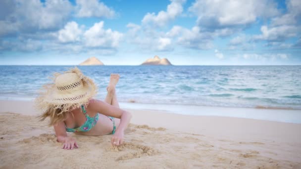 オアフ島のビーチで黄金の砂にハートを描く揚げたわら帽子の笑顔の観光客 愛と幸福という概念 ランカイビーチモッケン島の景色を眺める女性旅行者 ビーチで日焼けする若い女性 — ストック動画