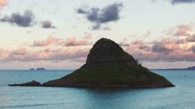 Oahu adasındaki ünlü Hawaii simgesinin manzarası. Çinlilerin Şapka Piramit Adası silueti sinema arka planında pembe renkli bulutlar. Kualoa Ranch 4K yakınlarındaki Kaneohe Körfezi 'ndeki Mokolii bazalt adası.