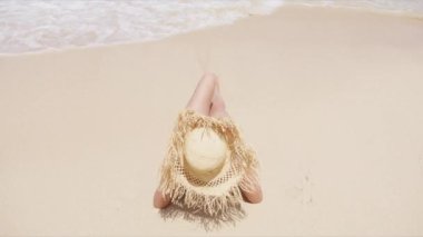 Üst Manzaralı Kız, güçlü köpüklü okyanus dalgalarıyla yıkanıyor ve ıslanıyor. Komik seyahat turizmi geçmişi. Kumsalda geniş hasır şapkalı genç bir kadın yatıyor. Hawaii Oahu adasında yaz tatili