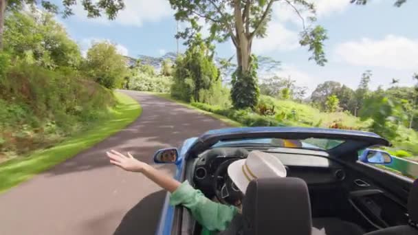 从敞篷车里伸出手来的自由女童军迎风驰骋 时尚的游客从没有屋顶的出租汽车中伸出手来 夏威夷路上在热带植物园开车的妇女 — 图库视频影像