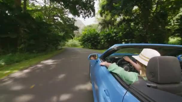 古色古香的女人带着山水在热带岛屿上旅行 夏威夷游客伸出手来晒太阳 开着蓝色敞篷车的快乐女孩享受夏天的日子 手牵着风 — 图库视频影像