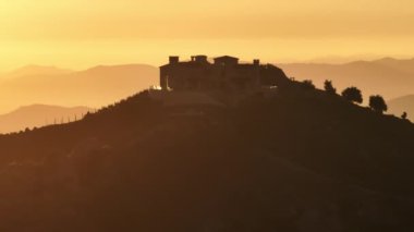 Malibu, California, ABD 'deki Malibu dağlarındaki Malibu Rocky Oaks Estate Vineyard' ın şarap imalathanesinin silueti. Gün batımında dağ tepelerindeki üzüm bağlarının insansız hava aracı görüntüleri. Şaraphane yapımı, 4K görüntü.