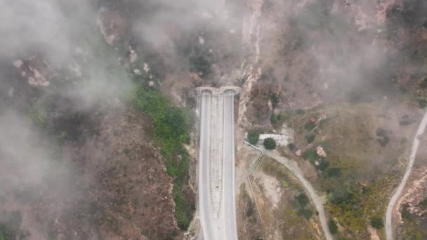 在美国加利福尼亚州洛杉矶郊区马利布的圣莫妮卡山脉的卡南路上飘扬的云彩的俯瞰 山区车辆隧道的空中景观 早上的天气 4K镜头 — 图库视频影像