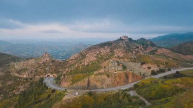 Malibu dağları, Kaliforniya, ABD 'de virajlı yolda giden arabaların panoramik görüntüleri. Malibu Rocky Oaks ve Estate Vineyard 'ın bulutlu bir akşamda dağın tepesindeki İHA çekimi. 4K görüntü.