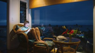 Odaklanmış adam, parlak ekran teknik cihaza bakıyor. Tropikal tatilde uzaktan çalışan işadamı. Gece geç saatlerde tablet ekranda ya da sosyal medya blogunda yazan rahat erkek.