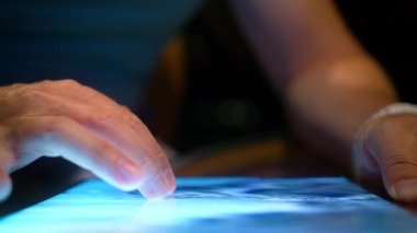Geceleri WiFi kullanan bir adam 3 boyutlu dünya haritasında bir yer arıyor. Seyahat rotasını internetten keşfeden adam. Modern teknoloji cihaz ekranı. Kapalı erkek parmakları tablet kullanarak uydu görüntüsü haritasında arama yeri