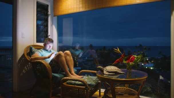 专心致志的人看着明亮的技术装置屏幕 商人在热带假期远程上网工作 深夜时分 在平板电脑屏幕电子邮件或社交媒体的博客内容上放宽了男性打字的限制 — 图库视频影像