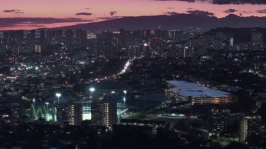 Şehir üzerinde gece aydınlanan pembe gün batımı manzarası. Pasifik 'teki Oahu adasının modern şehir manzarası. Honolulu şehir merkezinde gece manzarası. Honolulu 'nun başkenti ABD' nin üzerinde sinematik hava.