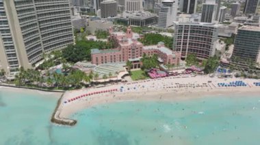 Okyanus manzaralı Hawaii pembe otel binası. Sihirli Waikiki sahilinde pahalı, pembe bir tatil köyü. Hawaii 'deki Oahu Adası ikonik oteli. Kumsalın keyfini çıkaran insanların üzerindeki havadan.