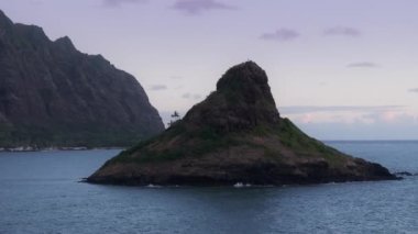Mokolii bazalt adasının kenarında, hareketli arka planında Kualoa Ranch Dağı olan iki palmiye ağacı. Çinliler, Pastel Pembe Gökyüzü 'nün arkasındaki piramit adasında. Hawaii Oahu Adası.