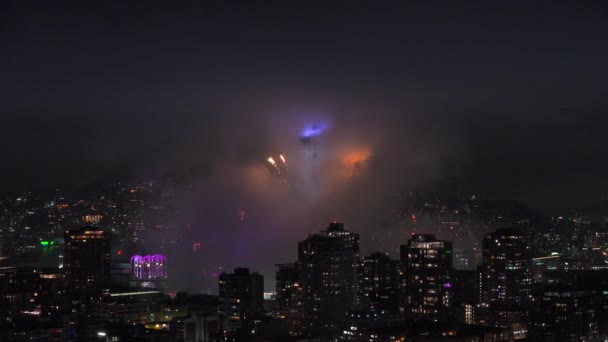 烟火陈列在照明的了望塔周围 2024年新年晚会上的烟火表演 西雅图市美丽的烟火表演 五彩缤纷的烟花在夜晚的云彩中爆炸 — 图库视频影像