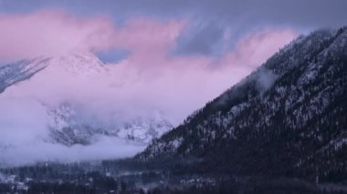 Gün batımında Washington dağları manzaralı pembe bulutlarla kaplıdır. Sinema kışı dağ manzarası, Kuzey Şelaleleri arka planı. Yüksek görkemli kış zirveleri üzerinde destansı pembe bulutlar.