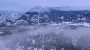 Sis Bavyera köyünün üzerinde sürünüyor. Arka planda Cascade Dağları ile Leavenworth 'da Kış Harikalar Diyarı. Havacılık kış sezonu Leavenworth Washington. Kışın bulutların arasında uçan drone