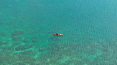 Lanikai sahilindeki turist turunda renkli bir kanoyla kürek çekerken mutlu ol. 4K saydam mavi sularıyla Oahu kıyısının havadan görüntüsü. Yaz gezisi. Her yere git. Açık hava sporları aktivitesi