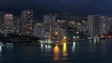 Şehir merkezinde, tropik ada Oahu 4K 'da. Gece Waikiki sahilinin manzarası. Geceleri aydınlatılmış güzel Honolulu modern binaları. Hava karardıktan sonra Hawaii 'nin en büyük şehrinden insansız hava aracı vuruldu.