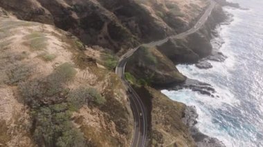 Oahu adası yolundan gidiyorum. Hawaii kıyısından geçen Rocky Dağı manzaralı bir araba. Manzaralı okyanus manzaralı güzel bir dağ yolu. Yolculuk. Sinematik kayalık okyanus kıyısından geçen hava manzaralı arabalar.