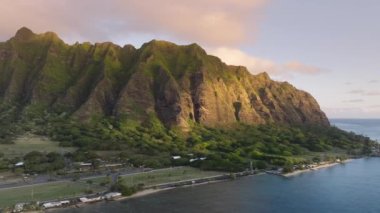 Güneşin doğuşundaki nefes kesici volkanik ada görüntüsü. Şafak vakti tropikal adada altın güneş ışığı altında dramatik bir şekilde yükselen sinematik tepeler. Jurassic Park 'ın yemyeşil manzarası