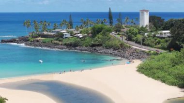 Oahu adasındaki Waimea plajında berrak mavi suyu olan mavi bir göl. Güneşli yaz gününde sinematik Waimea Körfezi Sahili. İnsanlar güzel kumlu sahilde tatilin tadını çıkarıyorlar. Manzaralı Havai Adası