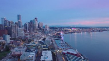 Seattle şehri geçmişi, ABD Washington. Gökyüzünün günbatımının mor renkleri. Seattle şehir merkezinin ufuk çizgisine hava görüntüsü kuruluyor. Modern mimari deniz manzaralı gökdelen ön plandaki cam binalar