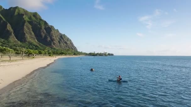 ハワイビーチにパドリングし 晴れた日の出に水から膨脹可能なボードを引っ張ります モーションバックグラウンドで映画のハワイの自然で若い男性の上のエピック航空 パドルボードにハンサムな男 — ストック動画