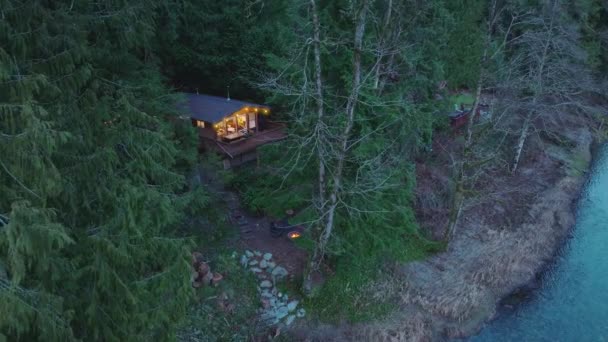 在神奇的华盛顿森林河流中的木制小木屋 有火坑的房子 小木屋隐藏在山林常绿树之间 晚上在森林中间的小木屋 — 图库视频影像