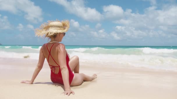 해변에 수영복과 모자에 소녀는 청록색 모래와 날씨와 경치를 감상합니다 — 비디오