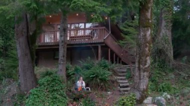 Hafta sonu orman kulübesinde ateş çukurunda elini ısıtan bir turist. Yanan ateşin keyfini çıkaran rahat bir kadın. Yeşil köknar ormanındaki ateş çukurunda kadın olan sinematik kukla anten.